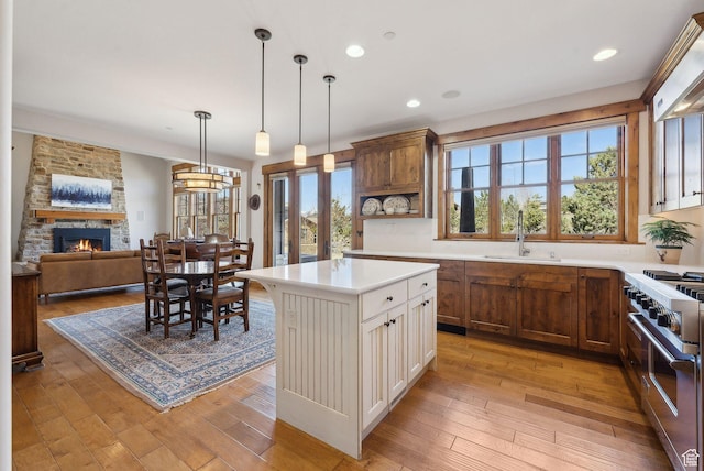 3250 E Thunderhawk Trl, Heber City, UT 84036 - kitchen featuring double oven range, a stone fireplace, hanging light fixtures, a sink, and light countertops