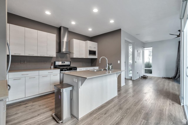 11611 S Alexandria W, South Jordan, UT 84009 - kitchen featuring white cabinetry, a sink, light wood finished floors, stainless steel appliances, and wall chimney exhaust hood