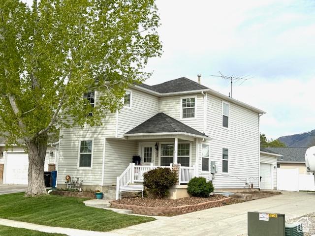 rear view of property featuring a lawn, a garage, covered porch, and driveway