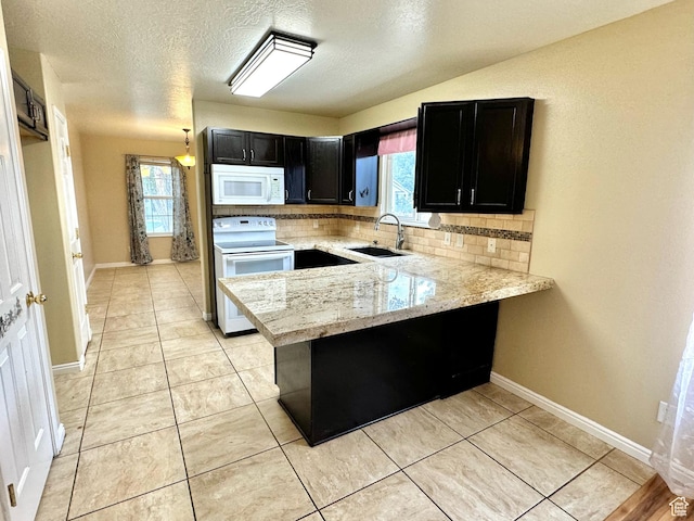 863 S 1520 E, Spanish Fork, UT 84660 - kitchen with tasteful backsplash, a sink, a peninsula, dark cabinetry, and white appliances