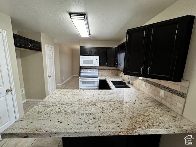 863 S 1520 E, Spanish Fork, UT 84660 - kitchen with decorative backsplash, a sink, light stone counters, dark cabinets, and white appliances