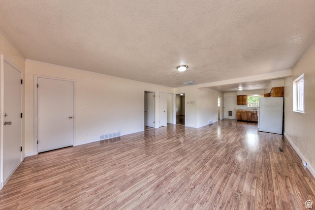 127 Birch Ave, Moab, UT 84532 - unfurnished living room with a textured ceiling, visible vents, baseboards, and light wood-type flooring