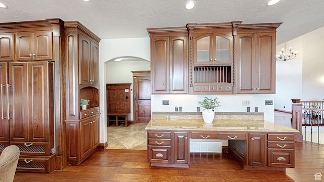 997 W 675 S, Mapleton, UT 84664 - kitchen with arched walkways, hardwood / wood-style flooring, light stone counters, glass insert cabinets, and a textured ceiling