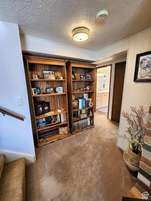 interior space featuring light carpet, a textured ceiling, stairway, and a decorative wall