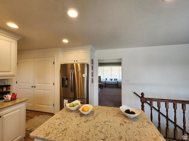 kitchen featuring stainless steel fridge, light stone countertops, recessed lighting, and white cabinets