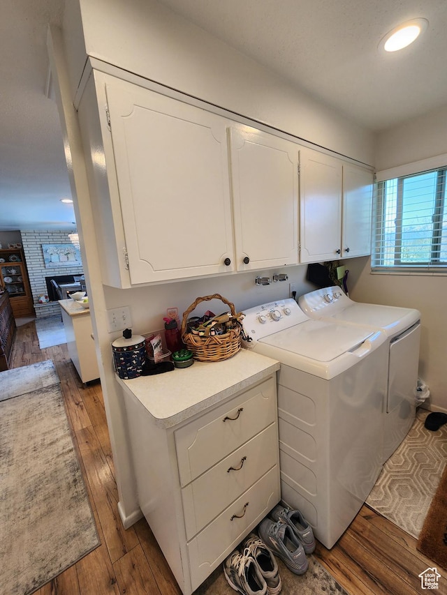 laundry room featuring cabinet space, washing machine and clothes dryer, wood finished floors, recessed lighting, and a large fireplace