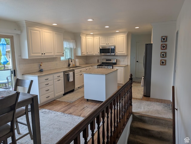 kitchen featuring appliances with stainless steel finishes, a sink, light wood-style floors, white cabinets, and recessed lighting