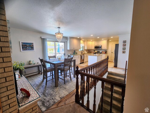dining space with a chandelier, a textured ceiling, recessed lighting, and light wood-style flooring