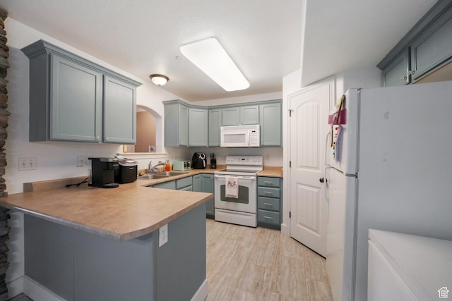 3569 E Rock Creek Rd Unit G2, Eagle Mountain, UT 84005 - kitchen featuring gray cabinets, arched walkways, a sink, a peninsula, and white appliances