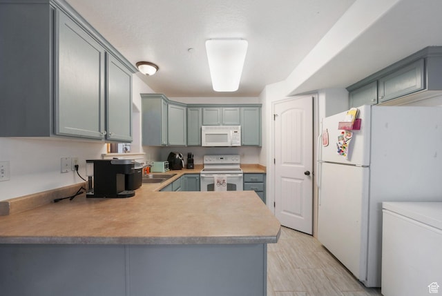 3569 E Rock Creek Rd Unit G2, Eagle Mountain, UT 84005 - kitchen featuring a peninsula, white appliances, light countertops, a sink, and gray cabinetry