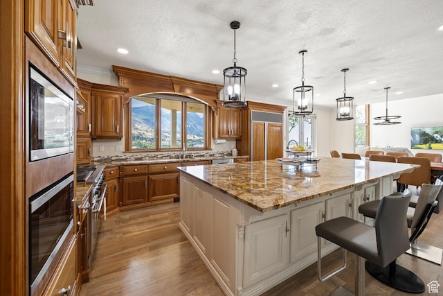 566 N Bella Vista Dr E, Orem, UT 84097 - kitchen with a textured ceiling, a spacious island, brown cabinetry, and a kitchen bar