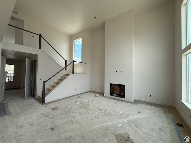 4097 N Ophir Dr, Eagle Mountain, UT 84005 - unfurnished living room featuring a towering ceiling, plenty of natural light, stairs, and a fireplace