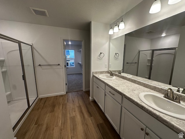1071 W 400 S Unit 44, Brigham City, UT 84302 - bathroom with wood finished floors, a shower stall, double vanity, baseboards, and a textured ceiling