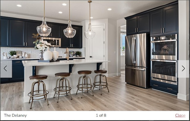 382 W 1225 N Unit 2, Harrisville, UT 84404 - kitchen with decorative backsplash, light countertops, a breakfast bar, stainless steel appliances, and light wood-style flooring