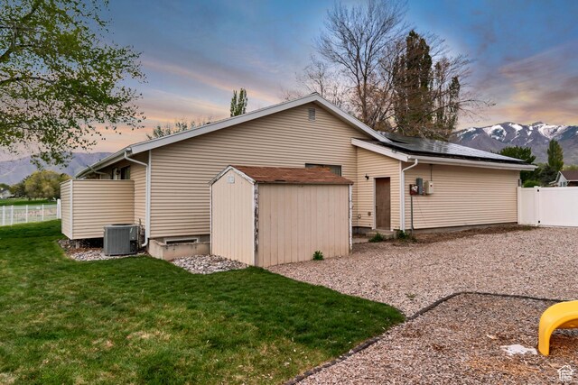 239 Country Club Dr, Stansbury Park, UT 84074 - back of property with a storage unit, solar panels, an outbuilding, central AC, and a mountain view