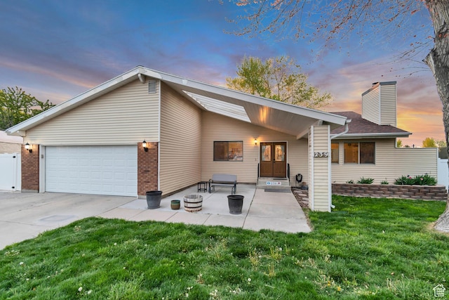 239 Country Club Dr, Stansbury Park, UT 84074 - view of front of home featuring a lawn, a chimney, concrete driveway, a garage, and brick siding