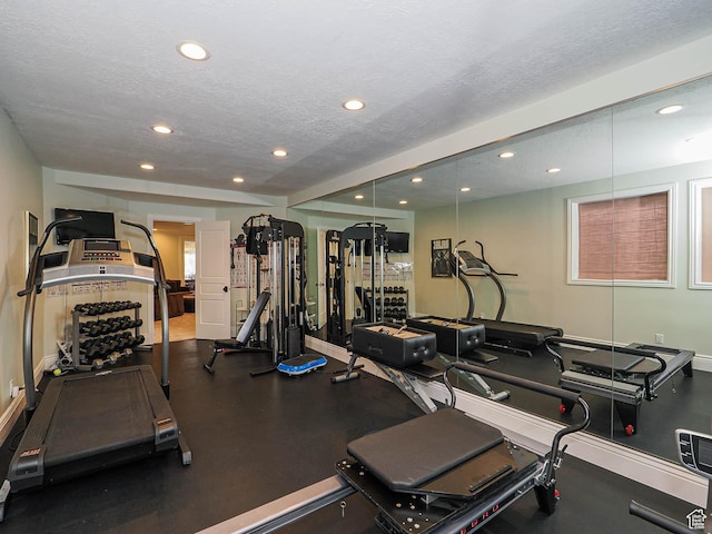exercise room with baseboards, recessed lighting, and a textured ceiling