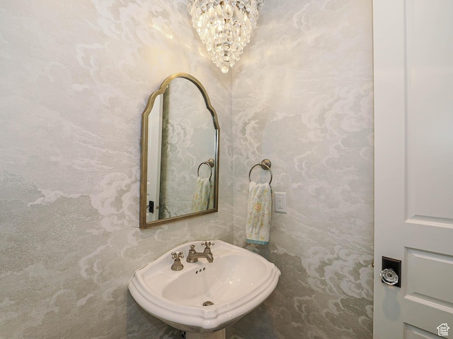 bathroom with a notable chandelier and a sink