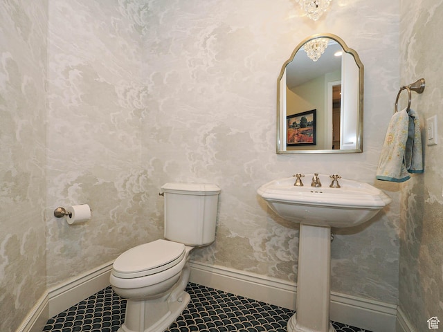 half bathroom featuring toilet, baseboards, and tile patterned flooring