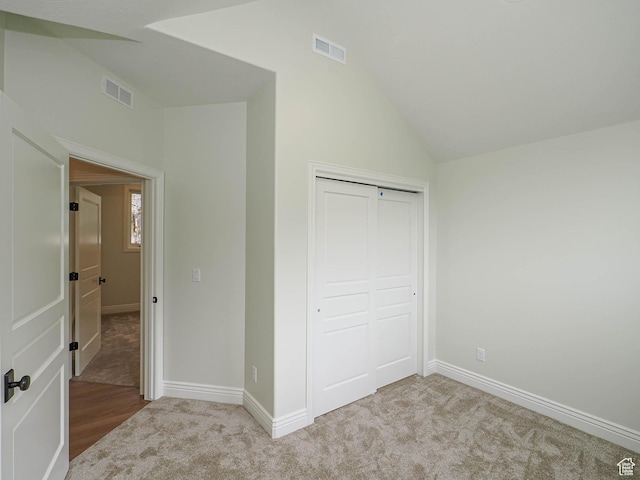 unfurnished bedroom with carpet, vaulted ceiling, and visible vents