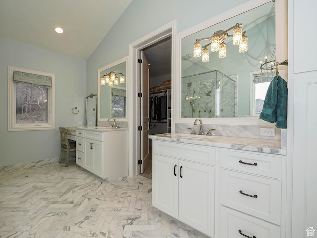 full bath with two vanities, a marble finish shower, a sink, and lofted ceiling