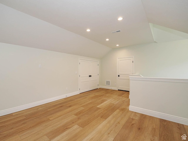 bonus room featuring baseboards, visible vents, vaulted ceiling, and light wood-style floors