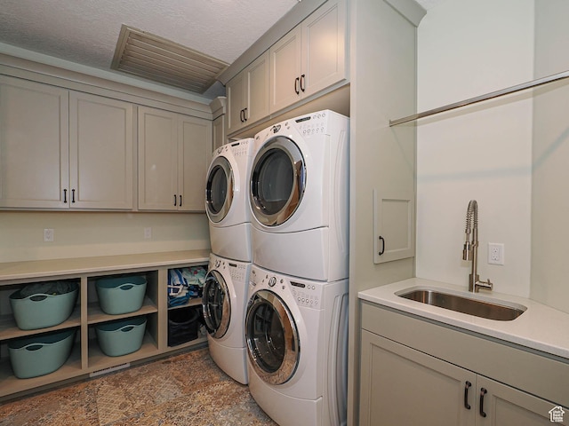 washroom with cabinet space, independent washer and dryer, stacked washer / drying machine, a sink, and stone finish flooring