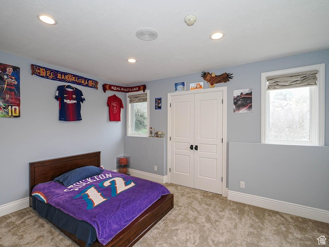 bedroom with recessed lighting, baseboards, light carpet, and a closet