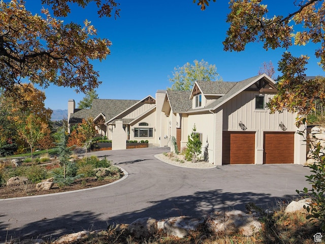 view of front of home featuring a shingled roof, board and batten siding, an attached garage, and aphalt driveway