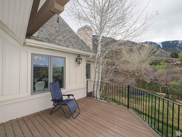 wooden deck with a yard and a mountain view