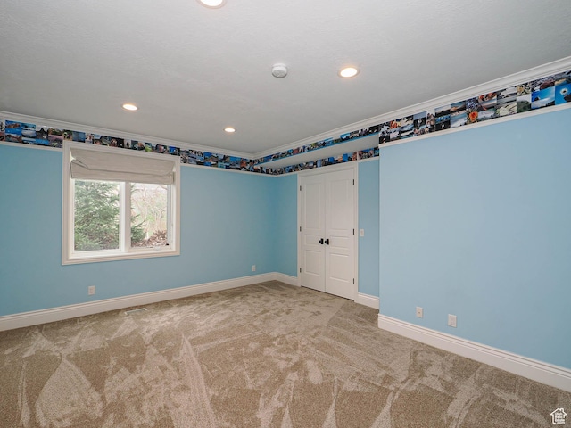 carpeted empty room with crown molding, recessed lighting, and baseboards