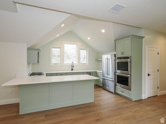 kitchen featuring appliances with stainless steel finishes, a sink, a peninsula, visible vents, and green cabinets