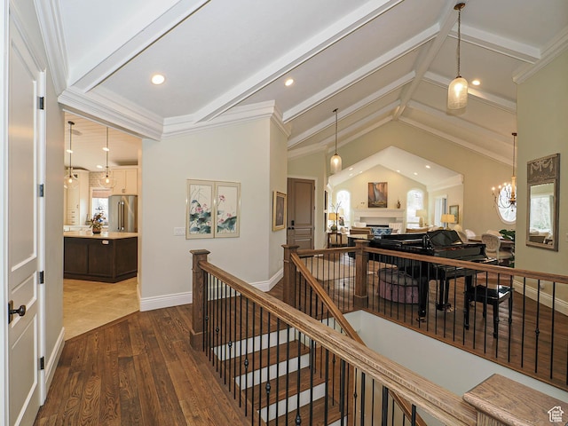 hallway featuring dark wood finished floors, ornamental molding, and an upstairs landing