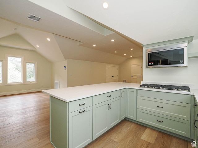 kitchen featuring appliances with stainless steel finishes, green cabinetry, visible vents, and lofted ceiling