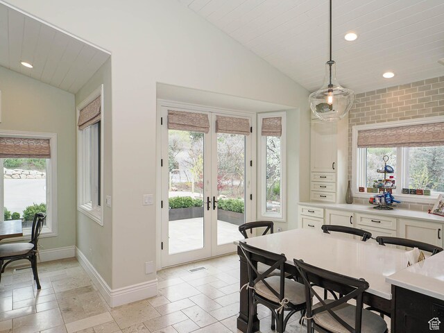 dining space with french doors, baseboards, stone tile flooring, lofted ceiling, and recessed lighting