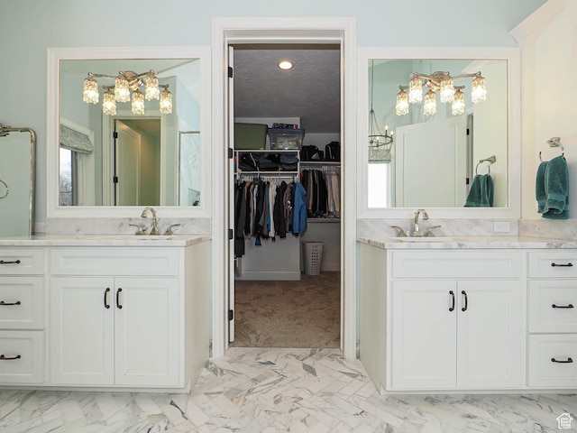bathroom featuring a sink, a walk in closet, and two vanities