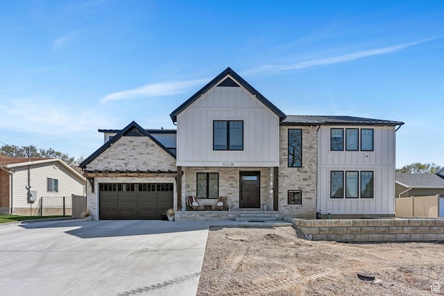 modern farmhouse style home featuring a garage, stone siding, board and batten siding, metal roof, and driveway