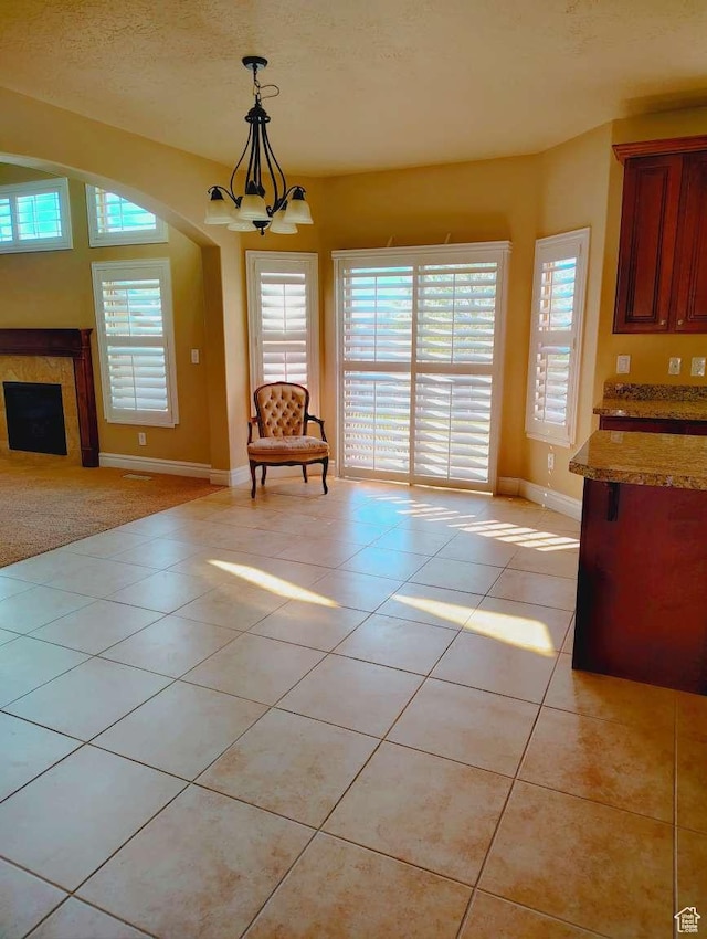 3641 W Canyon Lands Dr, Riverton, UT 84065 - unfurnished dining area with an inviting chandelier, baseboards, light tile patterned floors, and a fireplace