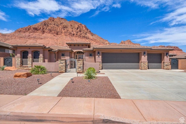 view of front of house featuring a mountain view, a gate, stone siding, and stucco siding
