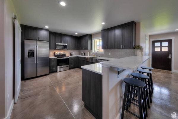 17 Tangren Cir, Moab, UT 84532 - kitchen featuring a kitchen breakfast bar, stainless steel appliances, a peninsula, finished concrete floors, and backsplash