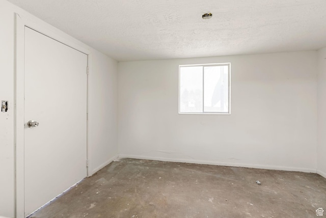 163 E 350 S, Logan, UT 84321 - unfurnished bedroom featuring baseboards, concrete flooring, and a textured ceiling