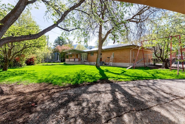 163 E 350 S, Logan, UT 84321 - back of house featuring a yard, brick siding, and a trampoline