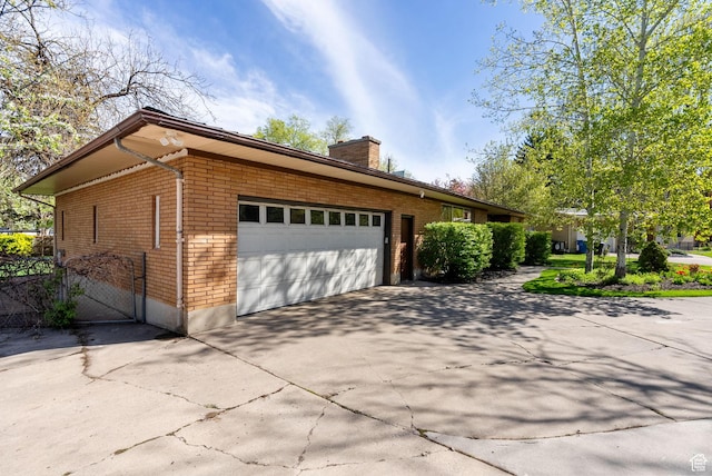 163 E 350 S, Logan, UT 84321 - view of side of home with brick siding, an attached garage, a chimney, and concrete driveway