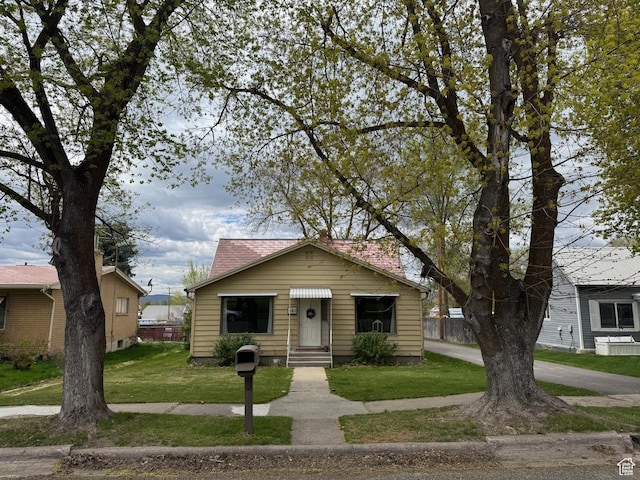 bungalow-style house featuring a front lawn and entry steps