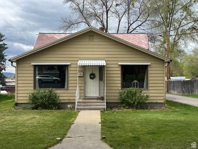 bungalow-style house featuring fence and a front lawn