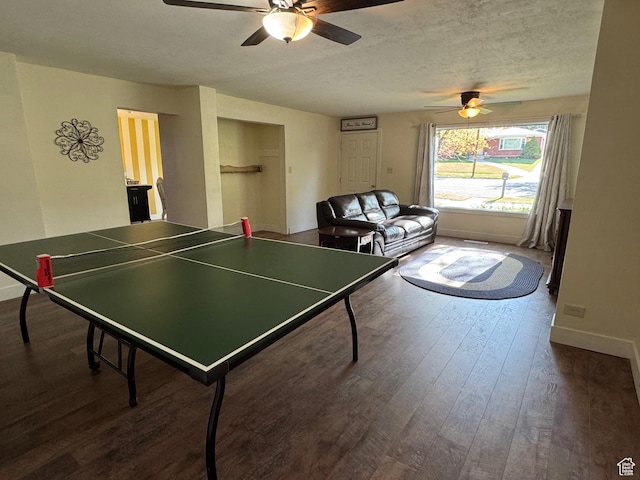 recreation room with baseboards, a ceiling fan, a textured ceiling, and dark wood-type flooring