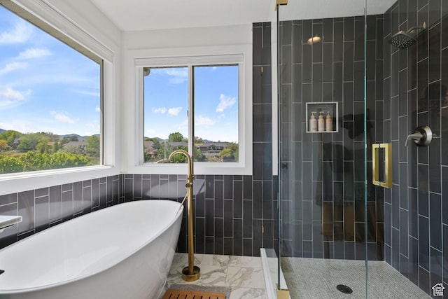 4356 W Elk Rim Rd, South Jordan, UT 84009 - full bathroom featuring marble look tile flooring, tile walls, a shower stall, and a freestanding tub