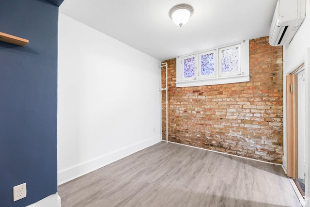 86 N B St Unit 11, Salt Lake City, UT 84103 - spare room with baseboards, brick wall, a wall mounted AC, and wood finished floors