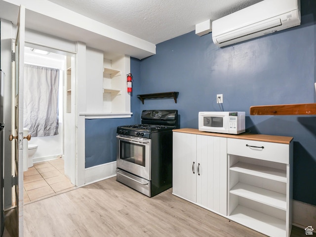 86 N B St Unit 11, Salt Lake City, UT 84103 - kitchen with open shelves, light wood-style floors, white microwave, stainless steel gas range, and an AC wall unit