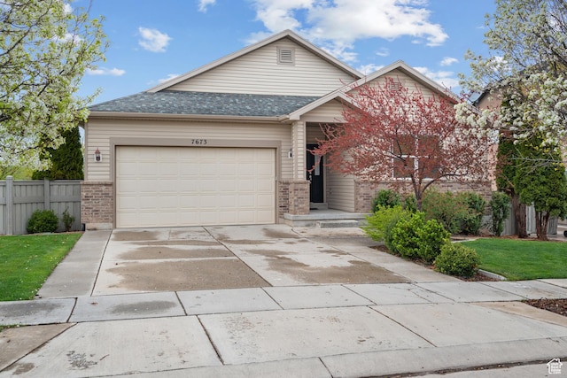 view of front of property with concrete driveway, brick siding, fence, and a garage